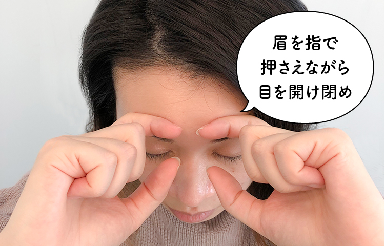 眉を指で押さえながら目を開け閉め